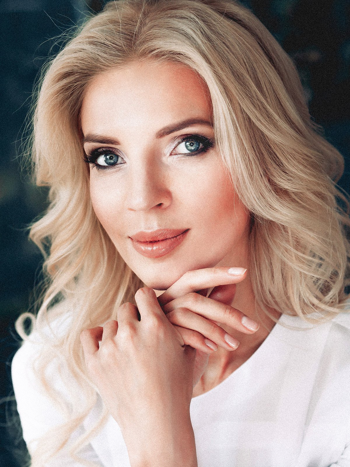 blonde facelift patient model with her hand under her chin smiling softly